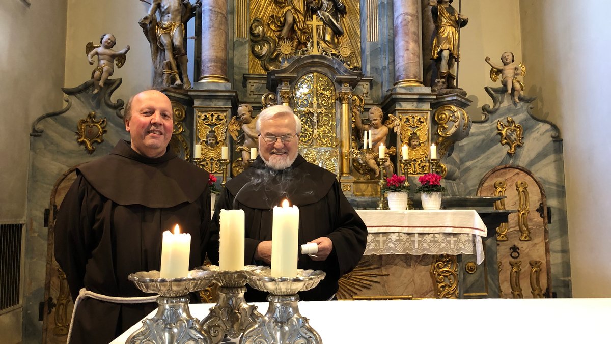 Zwei Franziskaner-Mönche vor dem Altar der Klosterkirche Engelberg