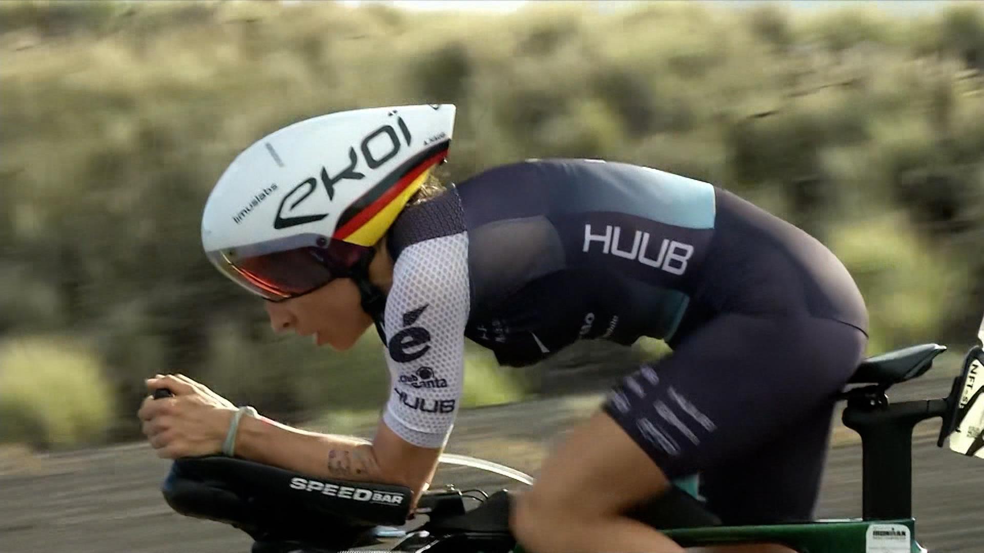 Eine Frau fährt Rennrad, im Hintergrund verschwommene Landschaft.