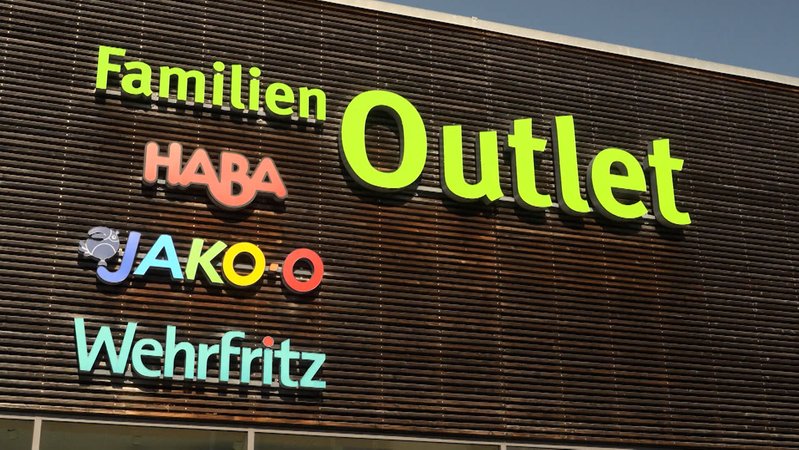 Auf einer Fassade sind in bunten Farben die Worte Haba, Jakoo, Wehrfritz und Outlet zu lesen.