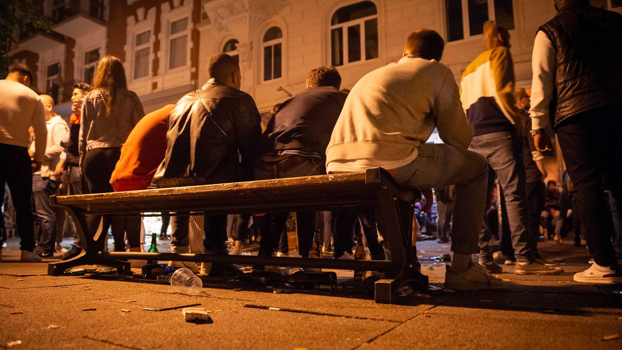 Mehrere Menschen sitzen nah beieinander auf einer Bank.