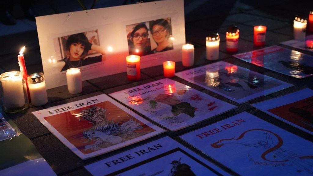 Kerzen vor den Bildern von Frauen und neben Schildern mit der Aufschrift "Free Iran"