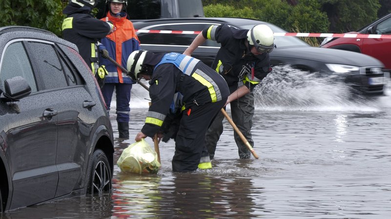 26.07.2025, Bayern, Nürnberg: Feuerwehrleute öffnen Gullys auf einer unter Wasser stehenden Straße. | Bild: Bernd März/extremwetter.tv/dpa 26.07.2025, Bayern, Nürnberg: Feuerwehrleute öffnen Gullys auf einer unter Wasser stehenden Straße.