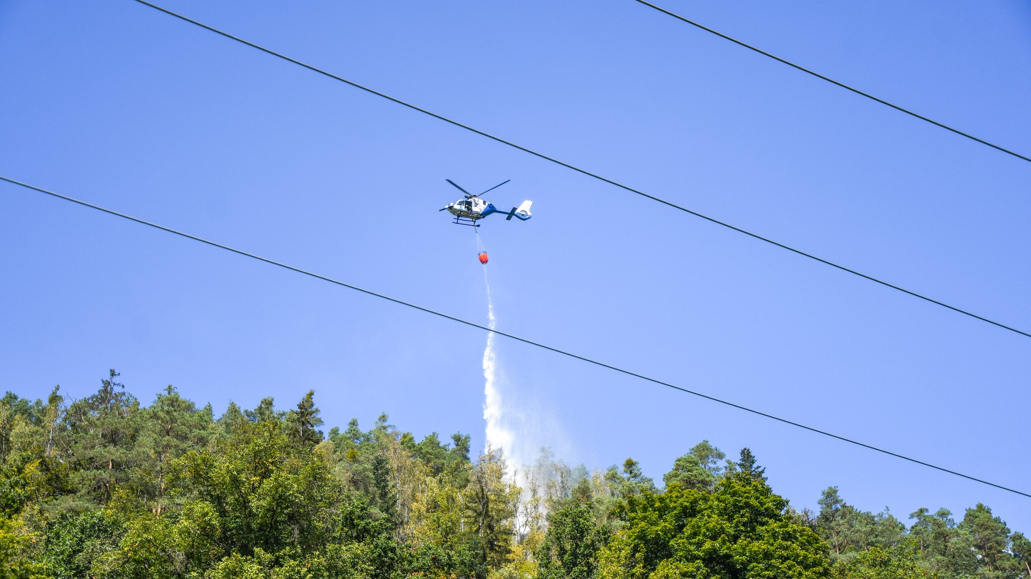 Hubschrauber lässt Wasser auf einen Waldbrand ab