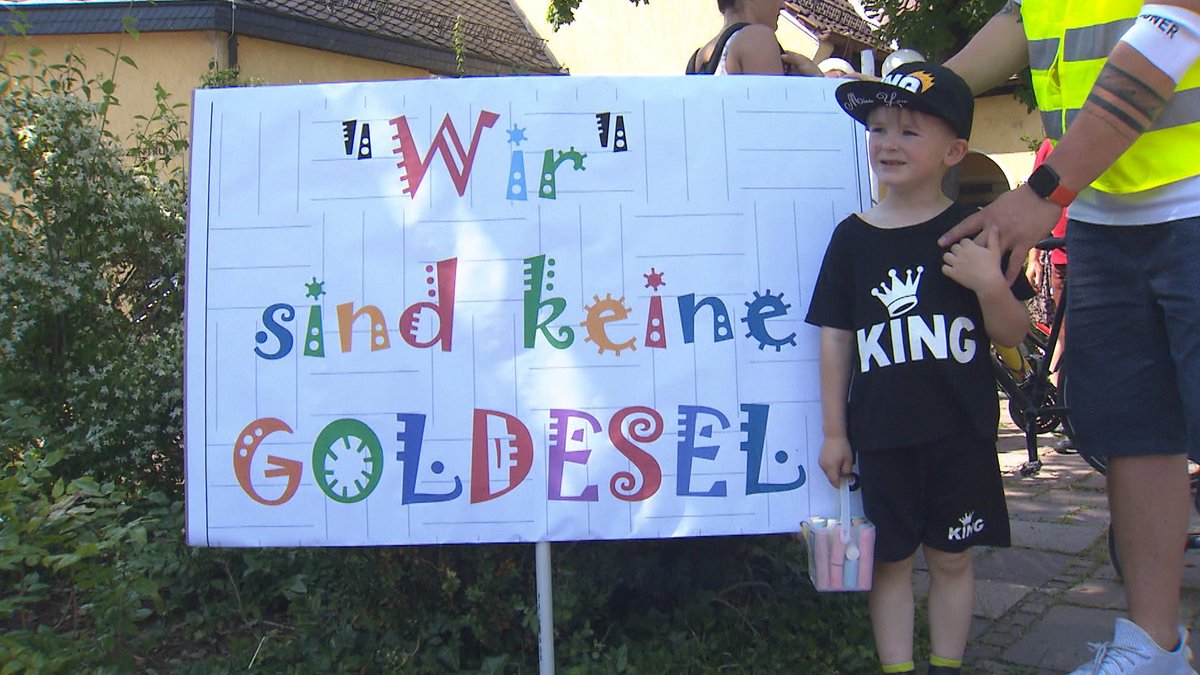 Ein Kind hält ein Schild hoch, auf dem steht "Wir sind keine Goldesel"
