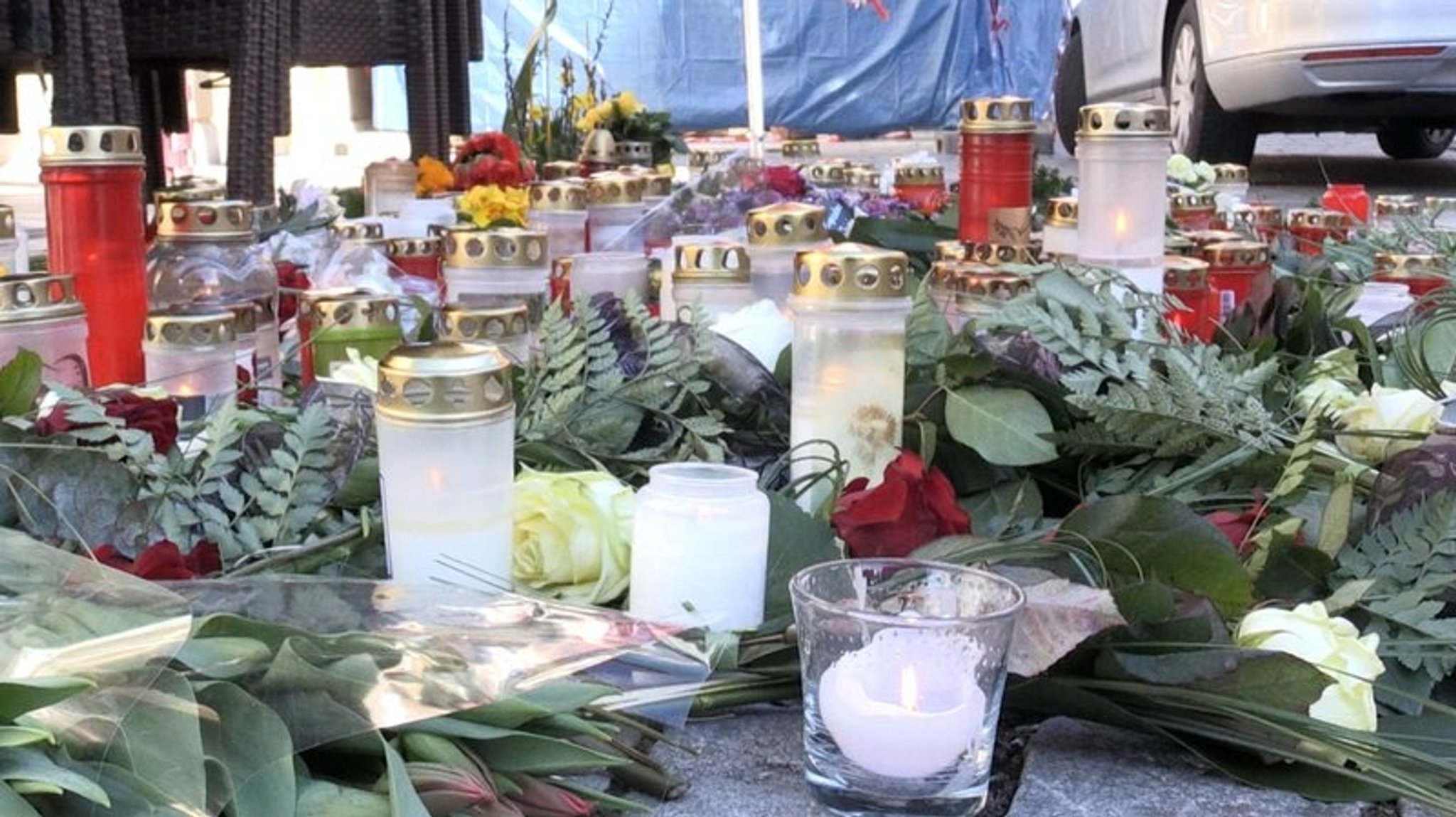 Blumen und Grabkerzen liegen auf dem Boden. 