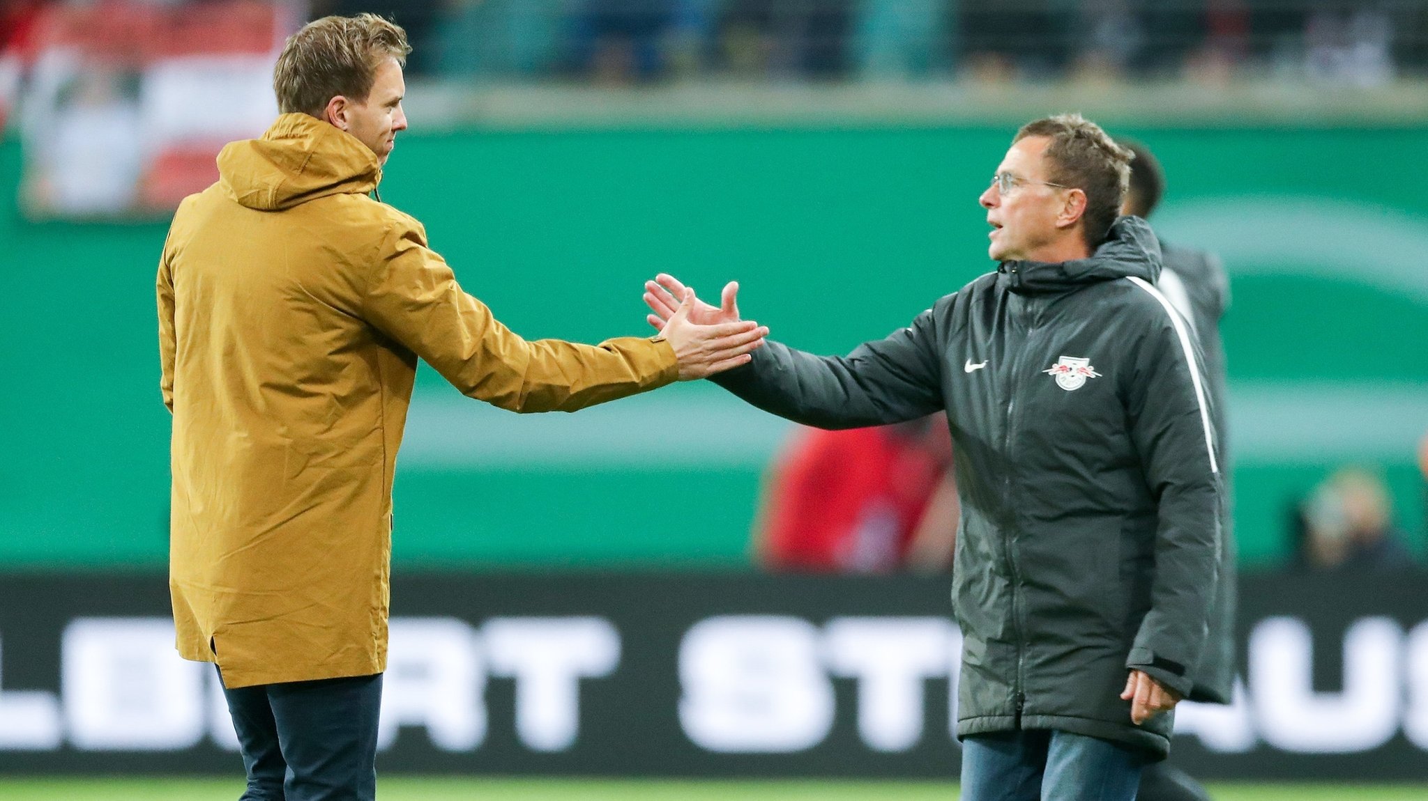 ARCHIV - 31.10.2018, Sachsen, Leipzig: Fußball, DFB-Pokal, 2. Runde, RB Leipzig - 1899 Hoffenheim in der Red-Bull-Arena Leipzig: Leipzigs Trainer und Sportdirektor Ralf Rangnick (r) und Hoffenheims Trainer Julian Nagelsmann geben sich nach dem Spiel die Hände. Am Dienstag treffen die beiden als Nationaltrainer aufeinander. 