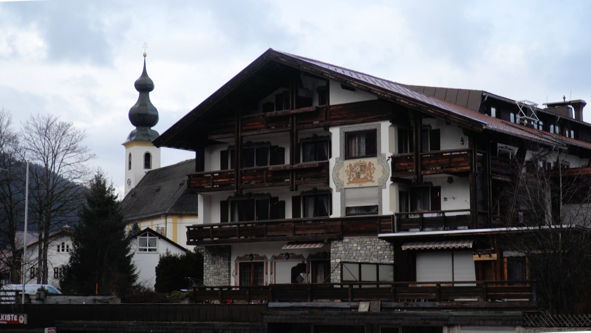 Ein Hotel im Alpenstil in Inzell, im Hintergrund eine Kirche.