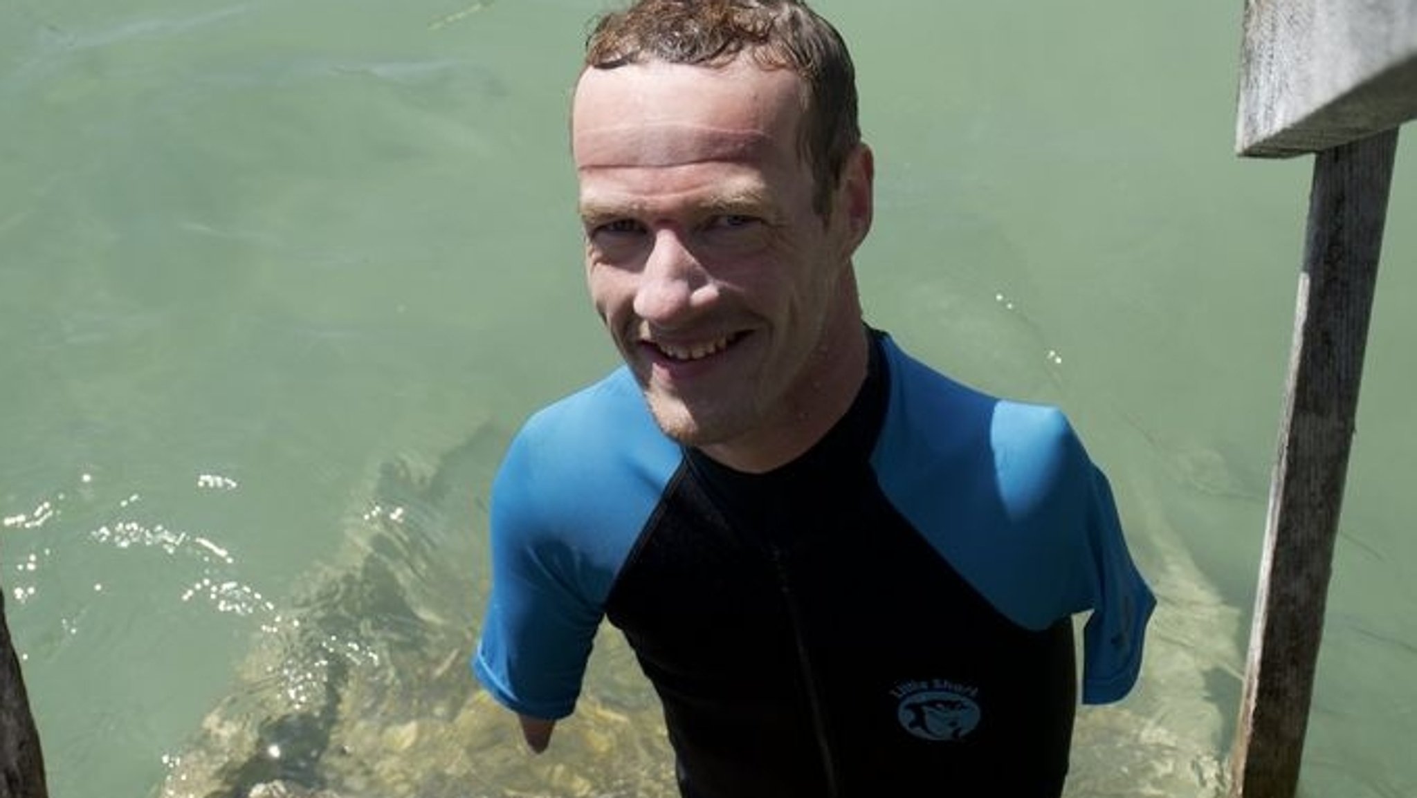 Janis McDavid lächelt im Wasser vom Starnberger See. Der ohne Arme und Beine auf die Welt gekommene Schwimmer hat den Starnberger See durchschwommen.