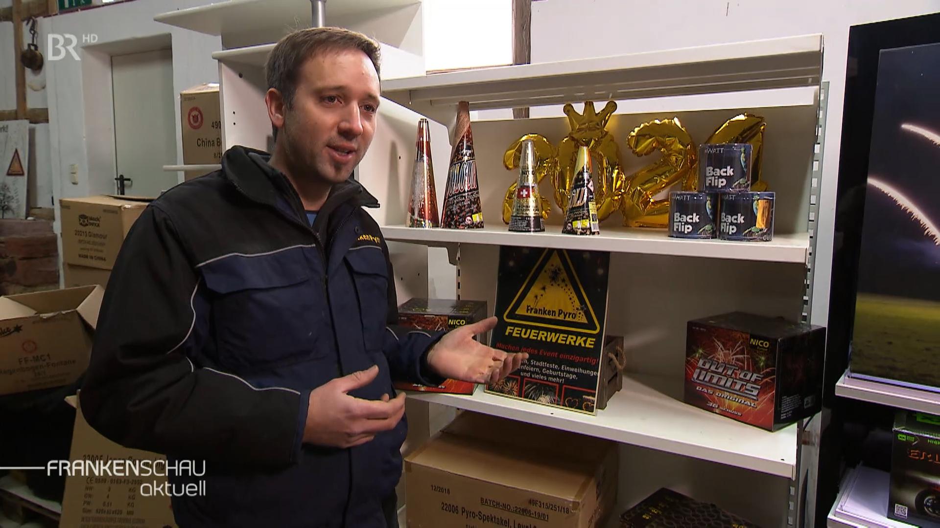 Jürgen Mattis steht vor einem Regal mit Feuerwerkskörpern.