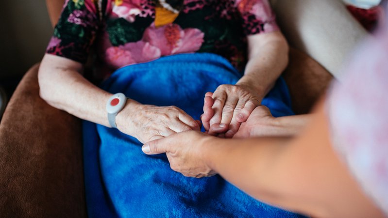 Pflege zu Hause: Eine alte Frau hält die Hände einer jüngeren Frau.