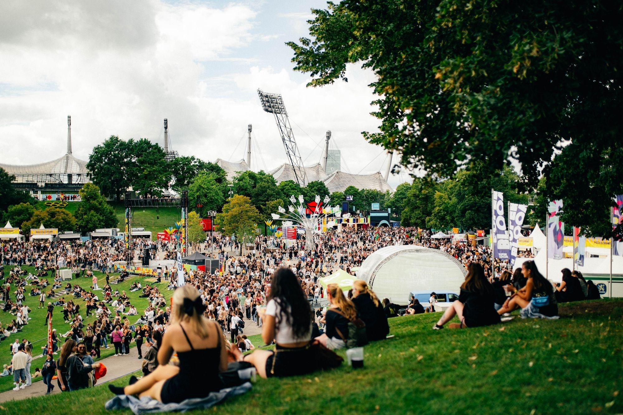 Menschen sitzen im Olympiapark während des Superbloom-Festivals 2025. | Bild:Superbloom/Fabian Stoffers