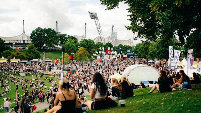 Menschen sitzen im Olympiapark während des Superbloom-Festivals 2025. | Bild: Superbloom/Fabian Stoffers Menschen sitzen im Olympiapark während des Superbloom-Festivals 2025.