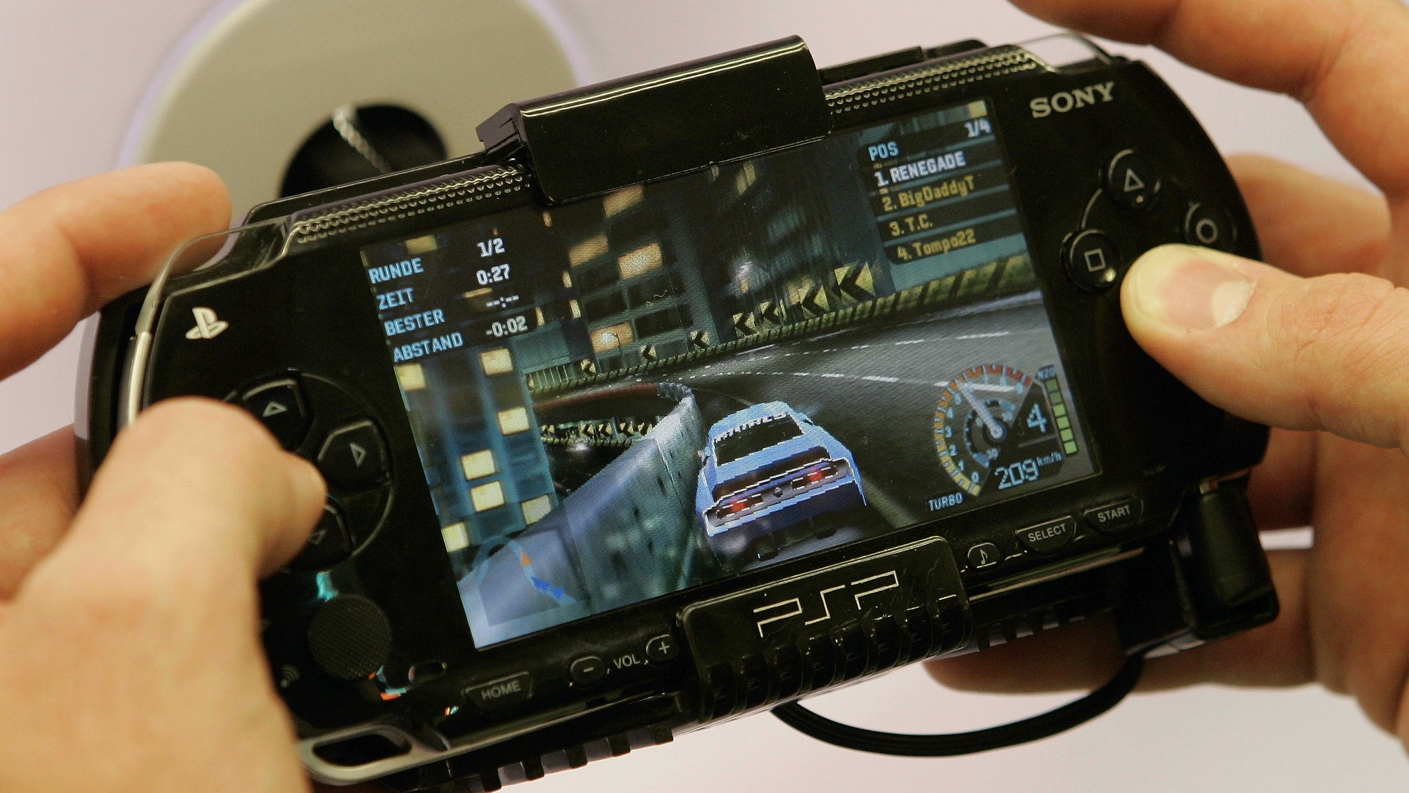 Ein junger Mann spielt ein Rennspiel mit der Sony Playstation Portable.