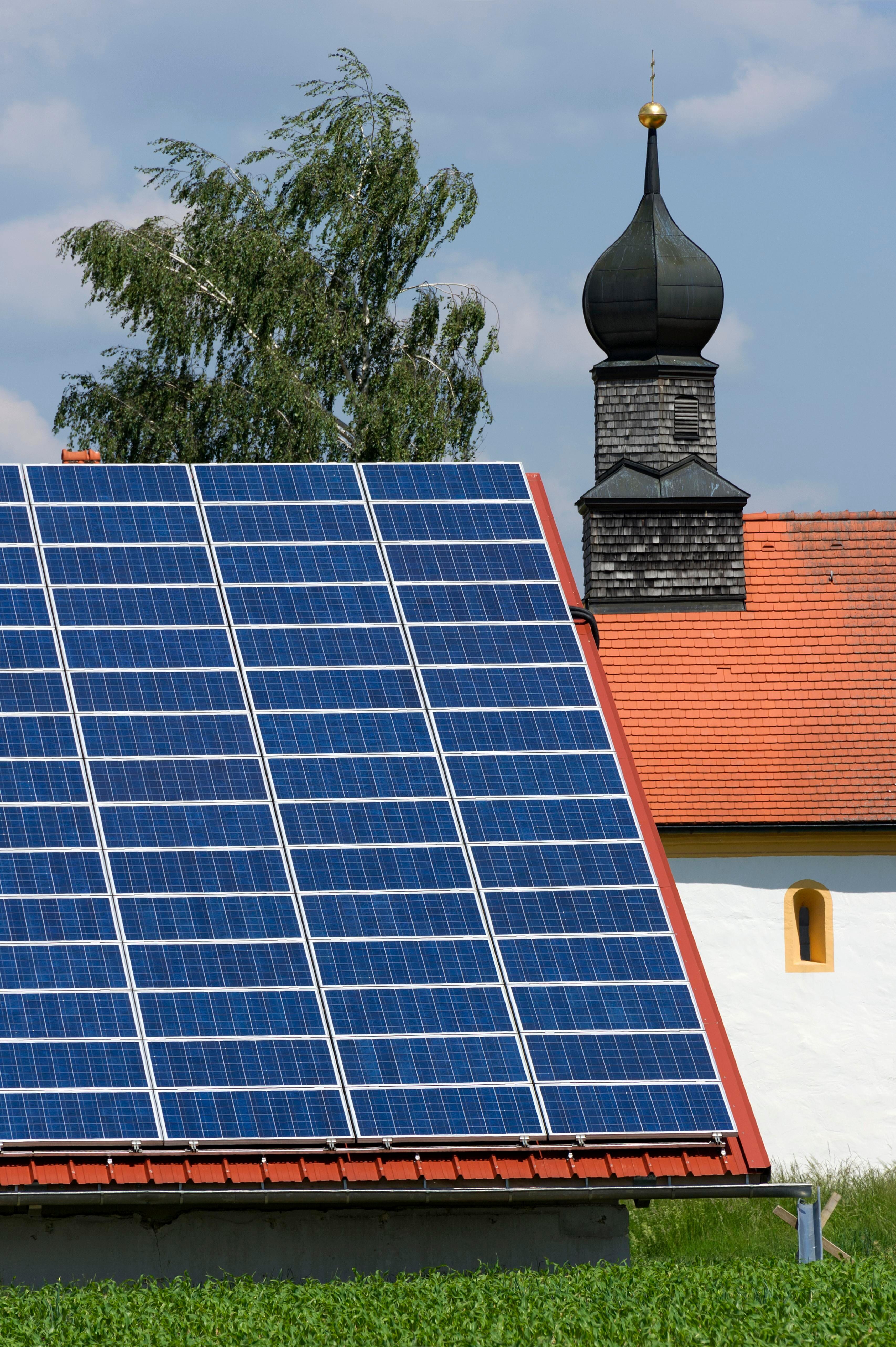 (Archiv- und Symbolbild) Photovoltaikanlage auf einem Dach, daneben eine Kirche (Archiv- und Symbolbild)