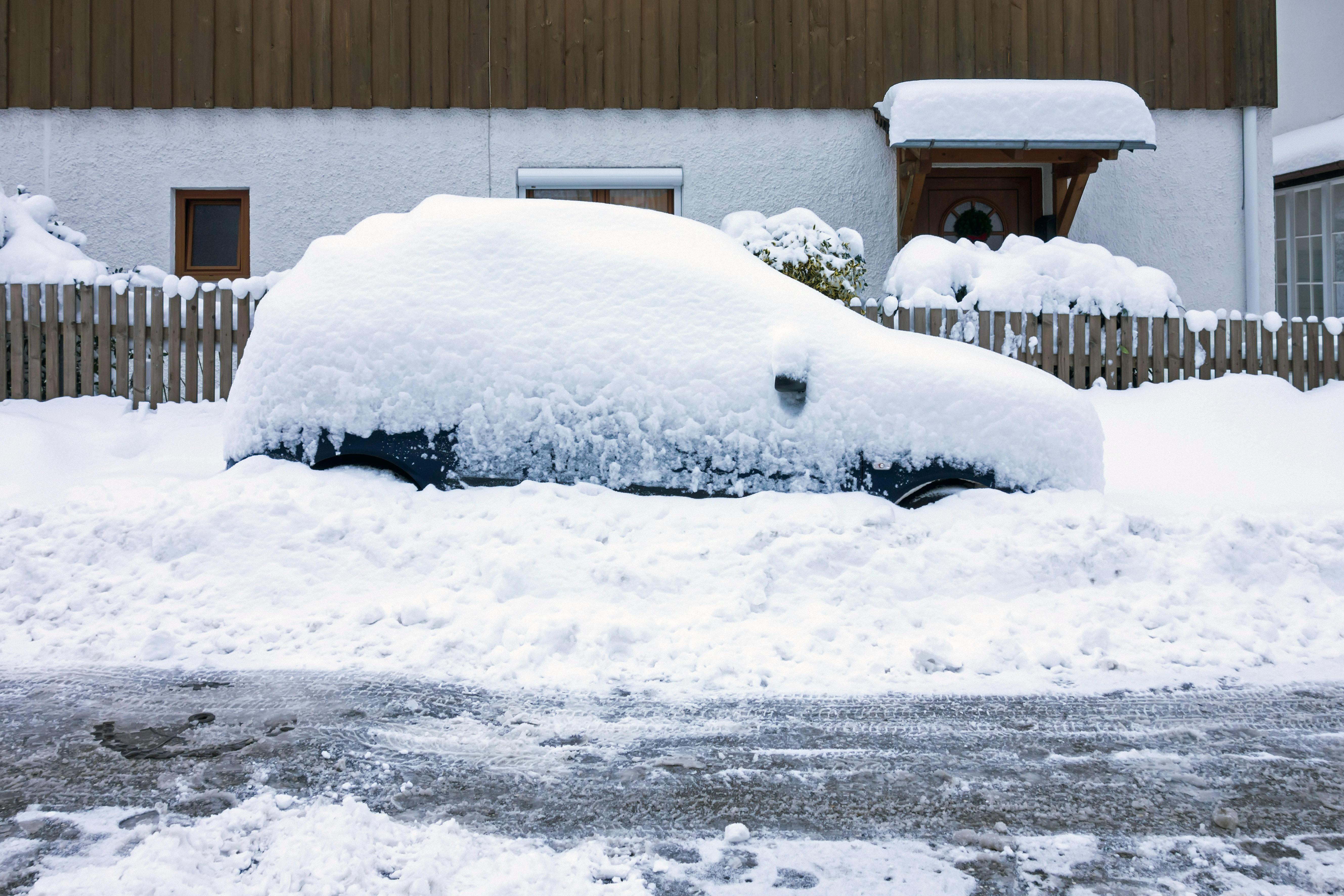 Schneebedecktes Auto am Straßenrand