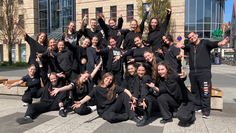 Schwarz gekleidete Tänzerinnen und Tänzer haben sich auf dem Nürnberger Kornmarkt zu einem Gruppenfoto aufgestellt.
