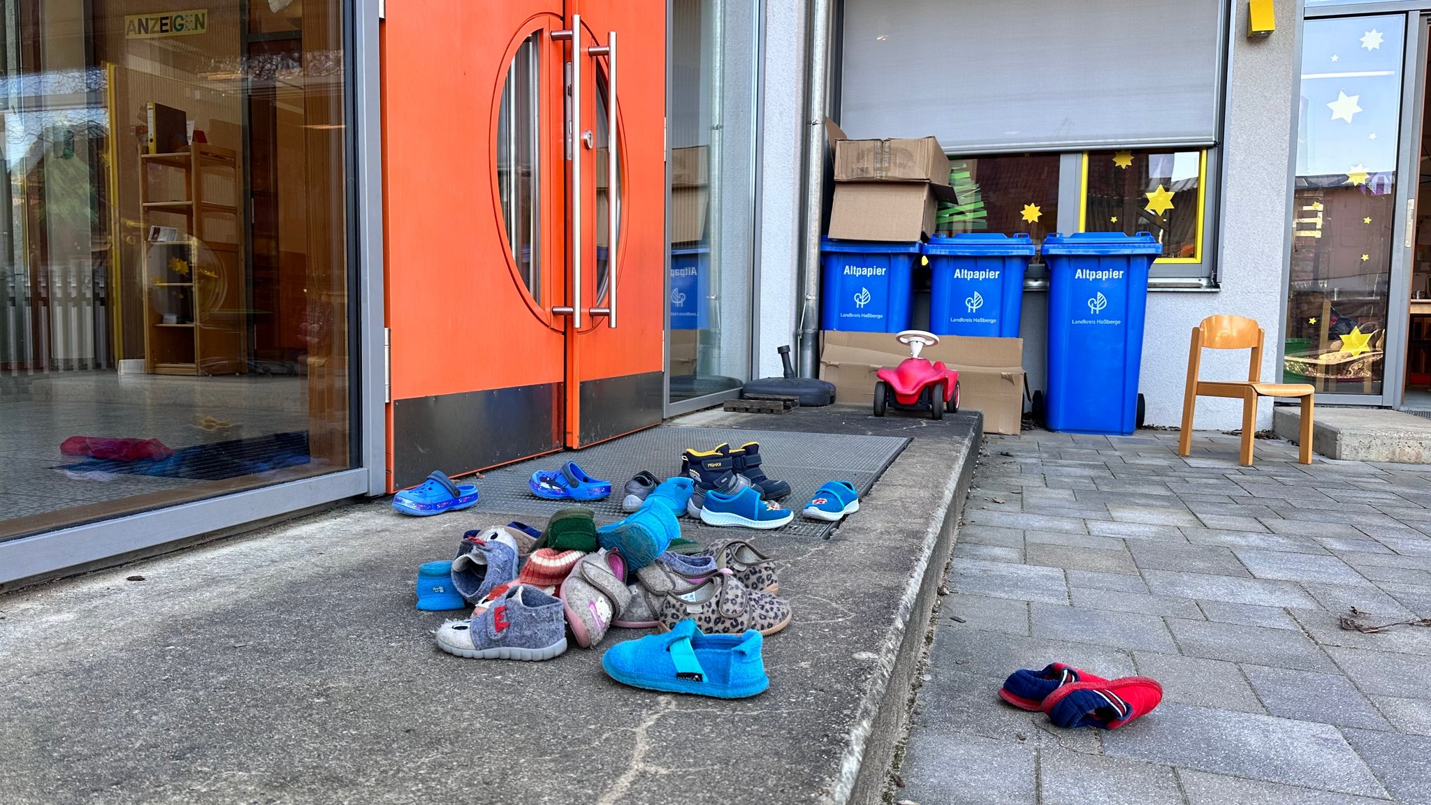 Hausschuhe von Kindern liegen vor der Kindergartentür. 