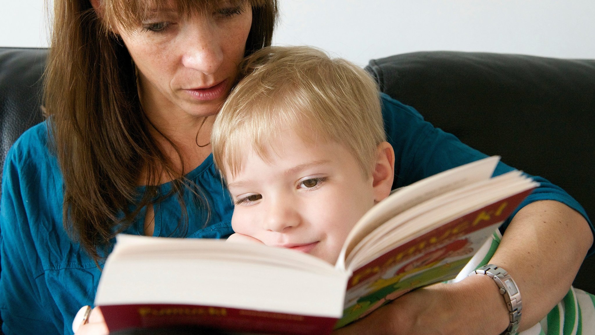 Eine Mutter liest ihrem kleinen Sohn aus einem Kinderbuch vor.