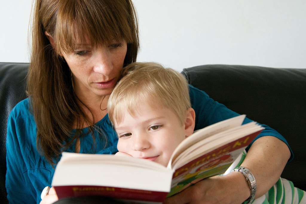 Eine Mutter liest ihrem kleinen Sohn aus einem Kinderbuch vor.