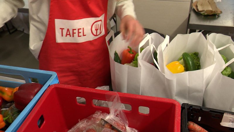 Eine helfende Person einer Tafel packt Essen in Tüten ab. | Bild: Bayerischer Rundfunk 2025 Eine helfende Person einer Tafel packt Essen in Tüten ab.