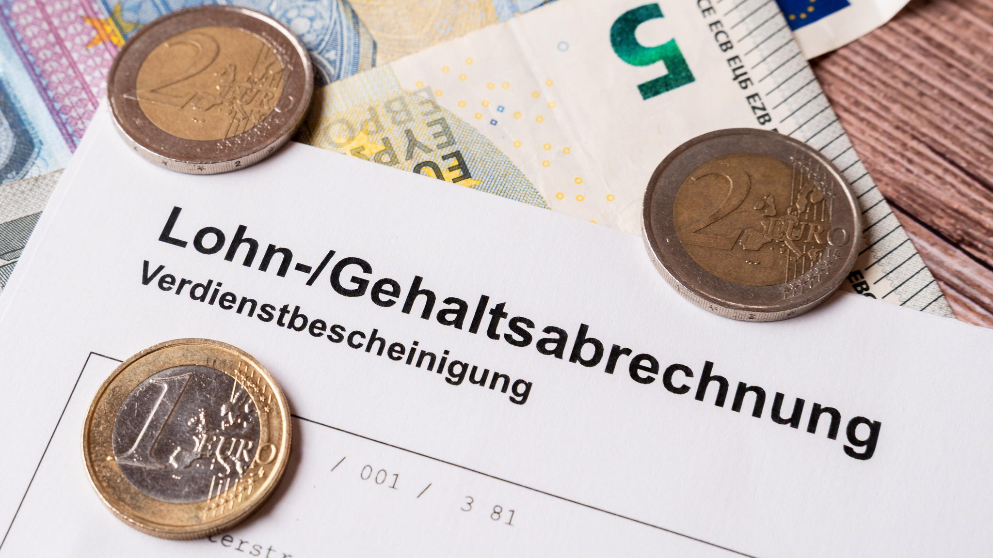 Nahaufnahme einer Lohn- und Gehaltsabrechnung mit Euro-Münzen und Banknoten | Bild: picture alliance / CHROMORANGE | MICHAEL BIHLMAYER Nahaufnahme einer Lohn- und Gehaltsabrechnung mit Euro-Münzen und Banknoten