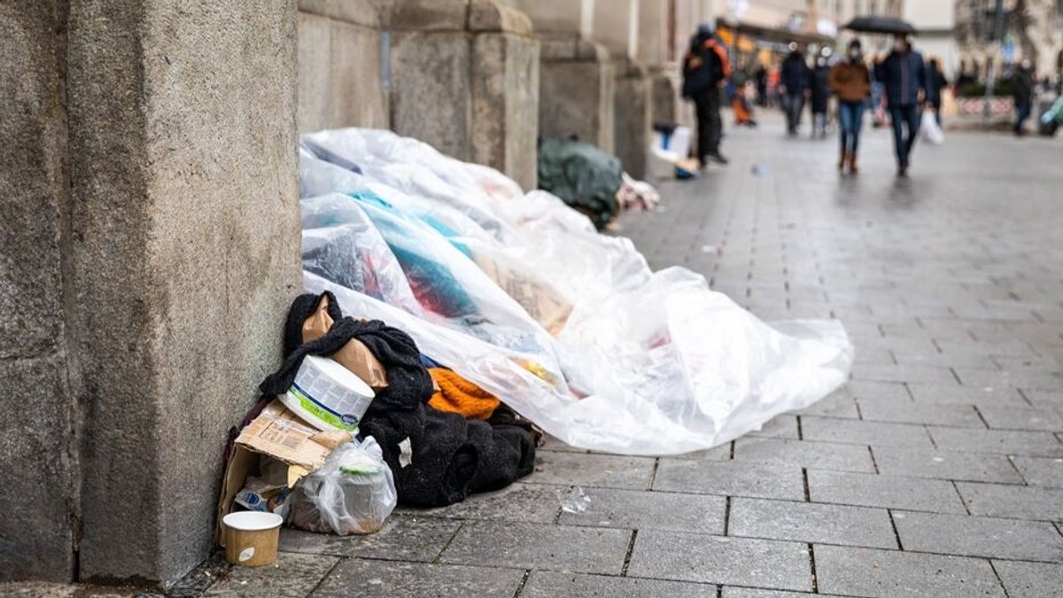 Ein Obdachloser unter einer Plane auf der Straße.