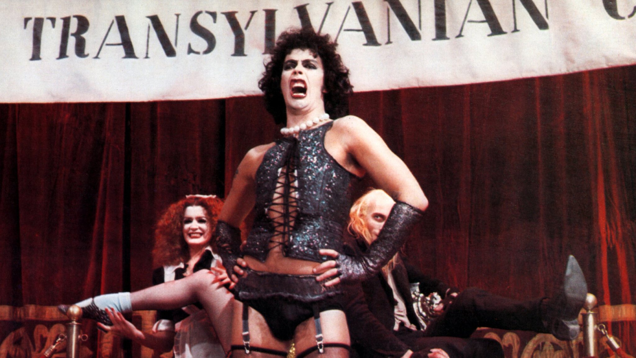 Tim Curry in seiner Rolle des Dr. Frank N. Furter, bekleidet mit Korsett und Strapse. | Bild: picture alliance/United Archives | United Archives/Impress Tim Curry in seiner Rolle des Dr. Frank N. Furter, bekleidet mit Korsett und Strapse.