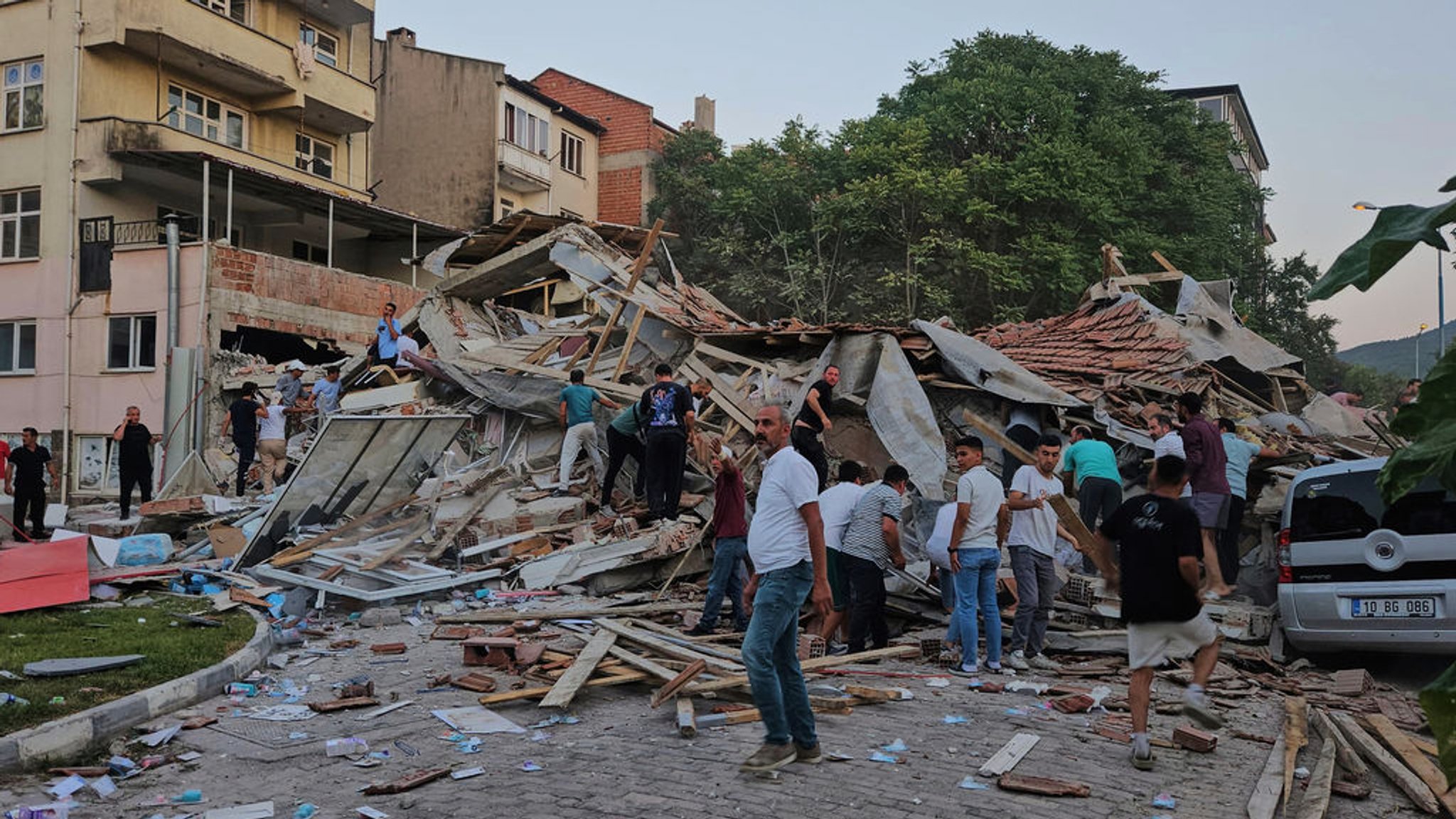 10.08.2025, Türkei, Sindirgi: Menschen beseitigen die Trümmer eines eingestürzten Gebäudes nach einem Erdbeben in Sindirgi in der Westtürkei. Foto: Bahadir Demirceviren/IHA/AP/dpa +++ dpa-Bildfunk +++