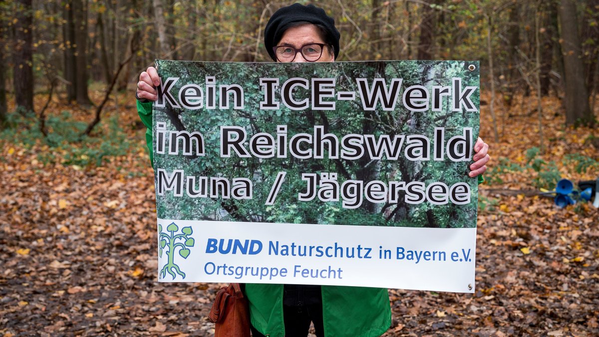 Eine Demonstrantin hält ein Plakat gegen das ICE-Werk im Reichswald in den Händen