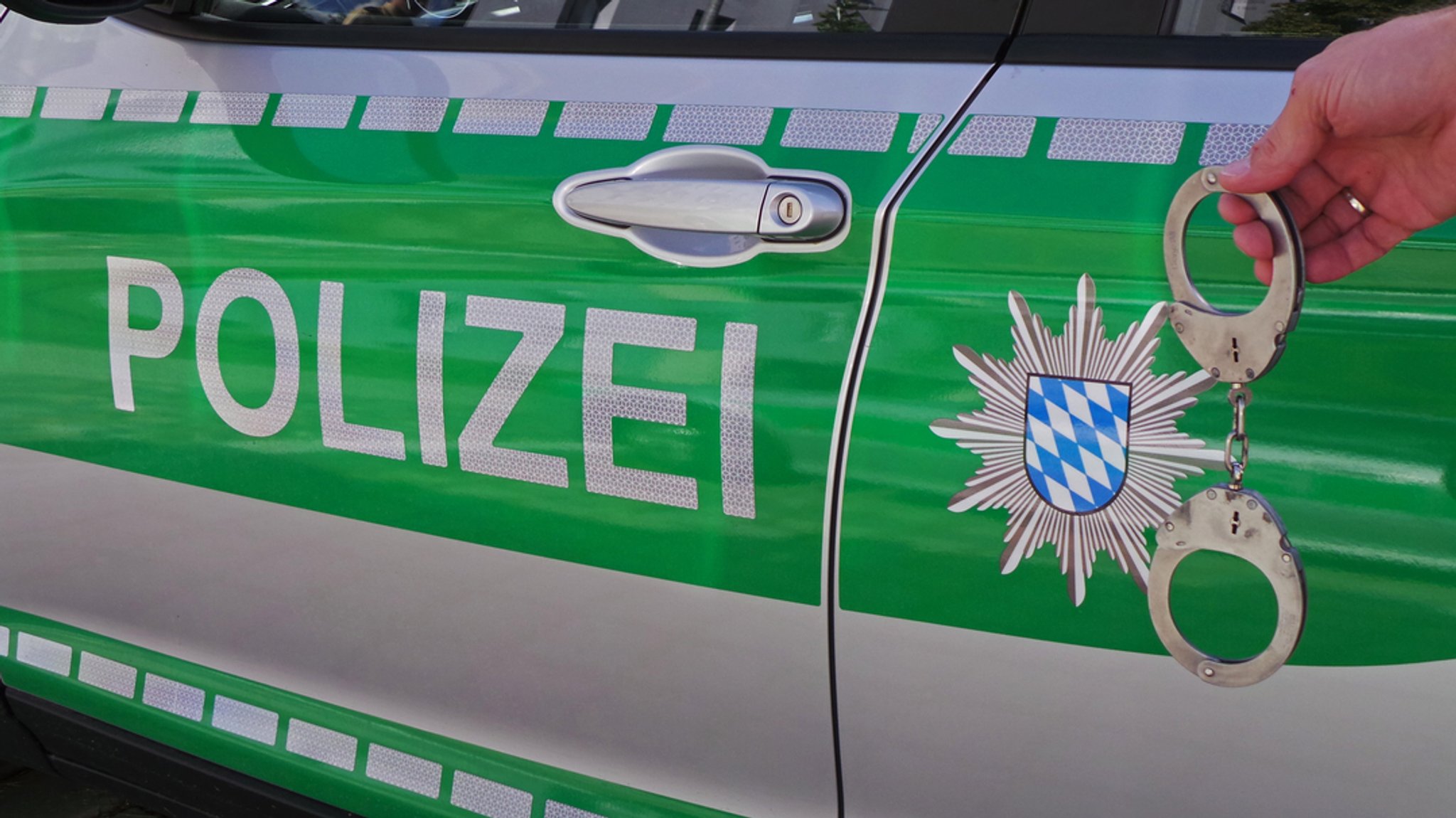 Handschellen vor einem Polizeiauto