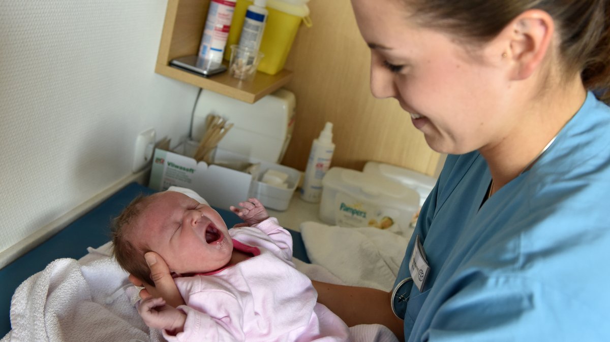 ARCHIV (23.10.2015): Hebamme hält ein Neugeborenes