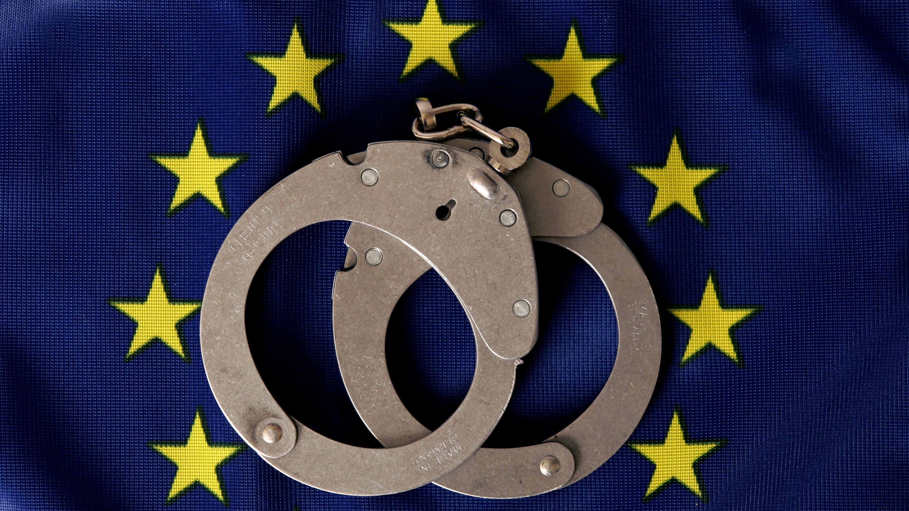 Ein Paar Handschellen liegt im Kreis der EU-Sterne auf einer Flagge | Bild: dpa / pa / Uli Deck Ein Paar Handschellen liegt im Kreis der EU-Sterne auf einer Flagge