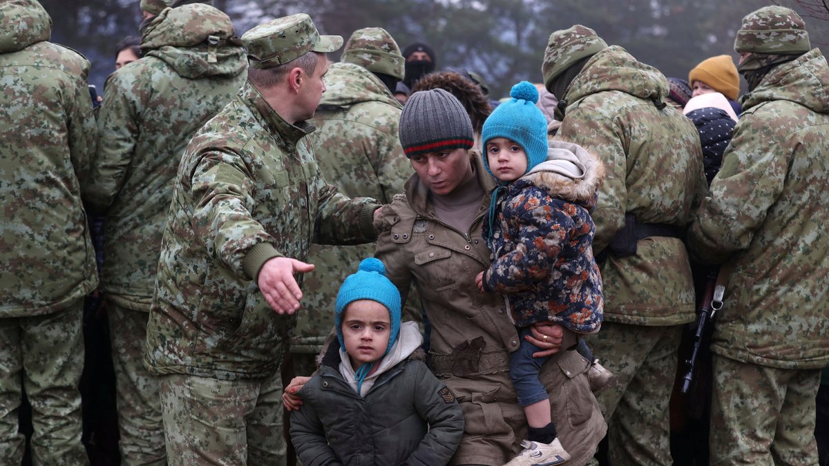 Migranten und belarussische Soldaten an der belarussisch-polnischen Grenze