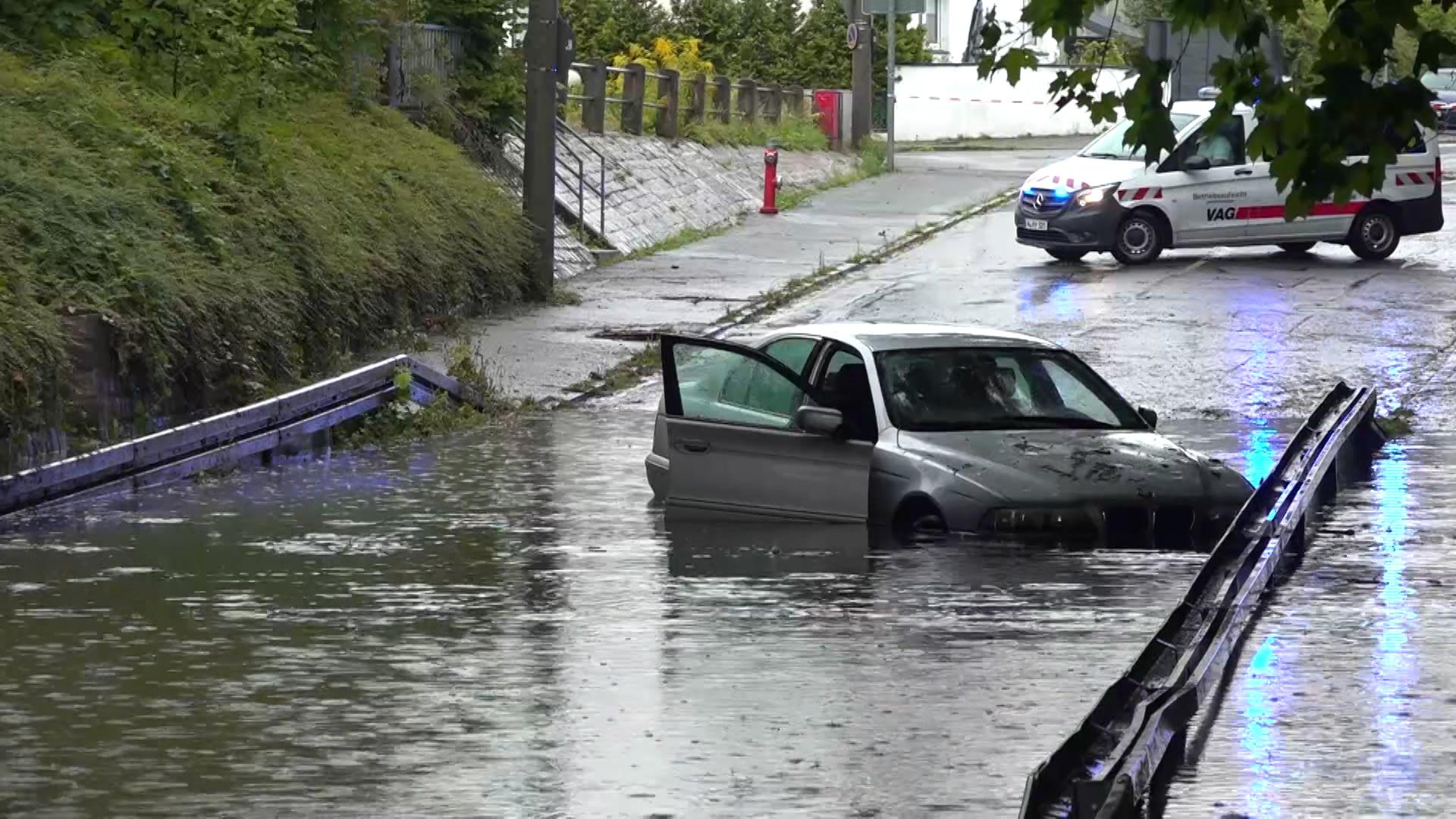 Die vollgelaufene Unterführung in Nürnberg mit einem Auto mittendrin.