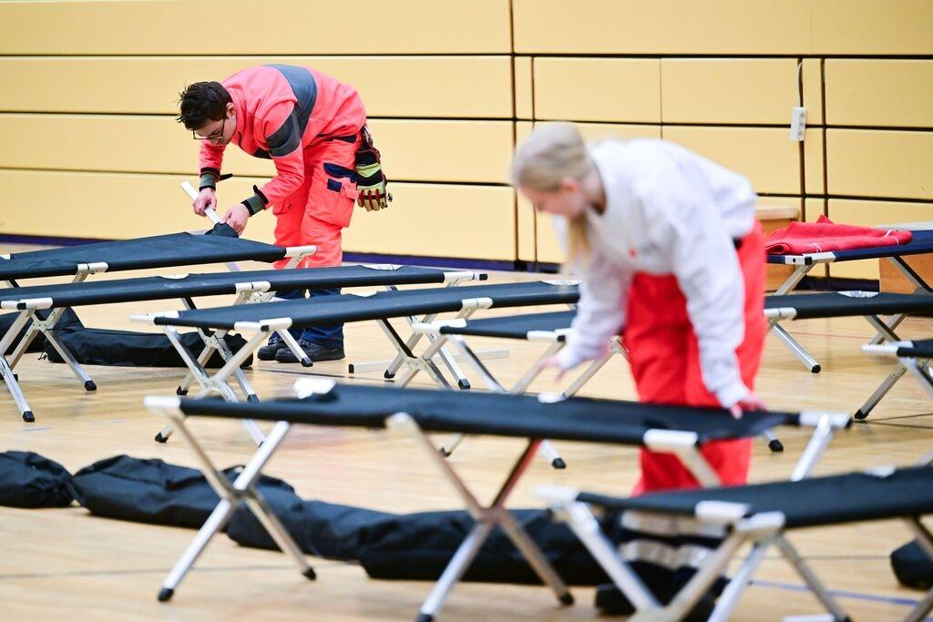 03.01.2026, Berlin: Ehrenamtliche Mitarbeiter des DRK bauen während eines Stromausfalls im Südwesten Berlins in einer Notunterkunft Feldbetten auf. Vom Brand einer Kabelbrücke sind 50.000 Haushalte und 2.000 Gewerbebetriebe betroffen. Foto: Sebastian Christoph Gollnow/dpa +++ dpa-Bildfunk +++