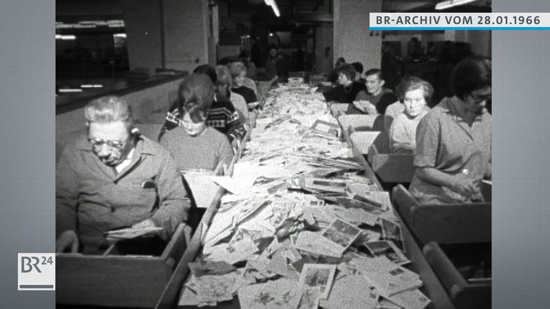 Post-Mitarbeiter am Fließband beim Sortieren von Briefen und Postkarten.