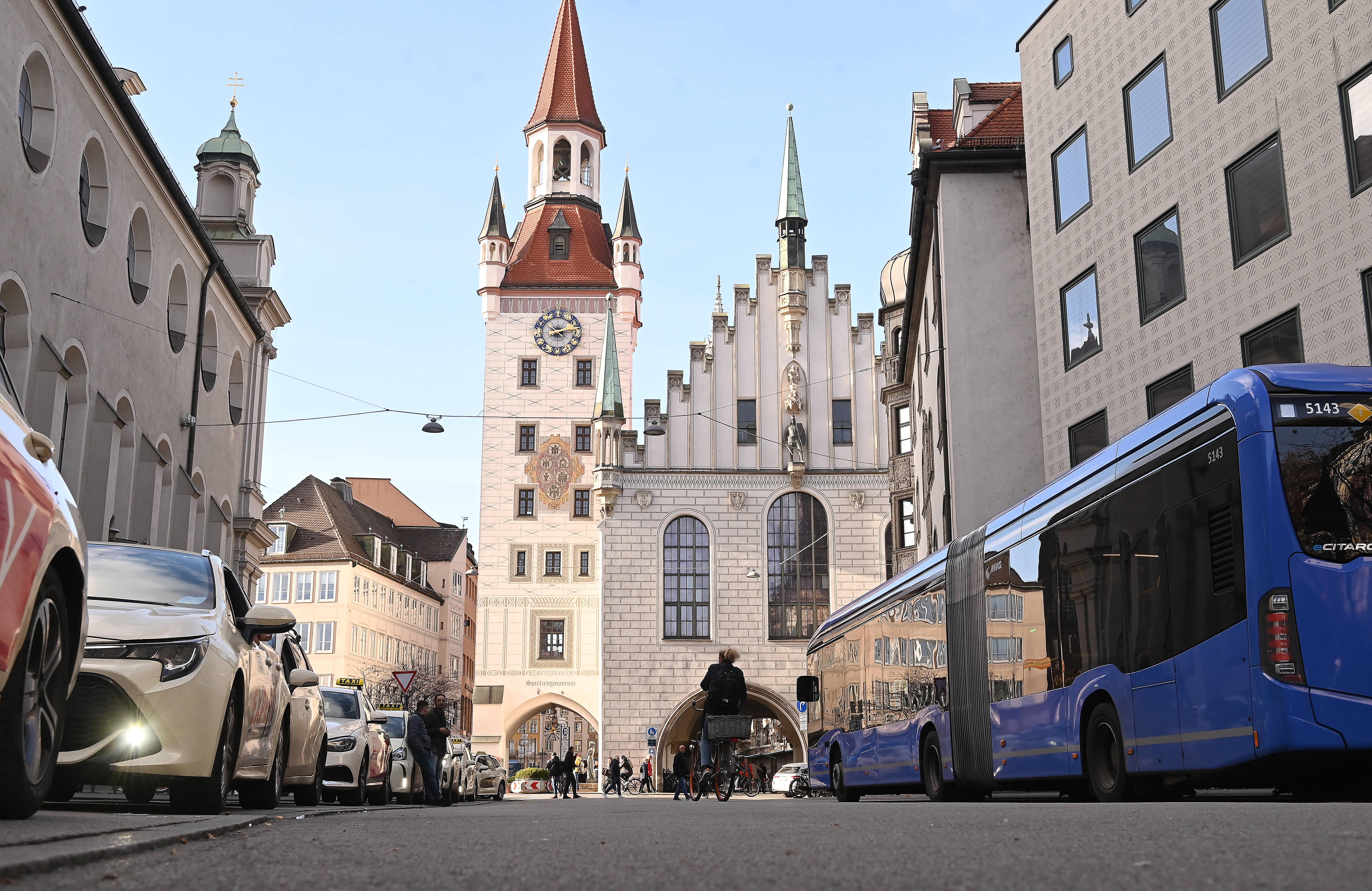 Blick aus der Froschperspektive auf das Alte Rathaus in München, auf der Straße davor parkende Autos und ein Bus. (Symbolbild) Die Münchner Altstadt soll fußgänger- und fahrradfreundlicher werden.