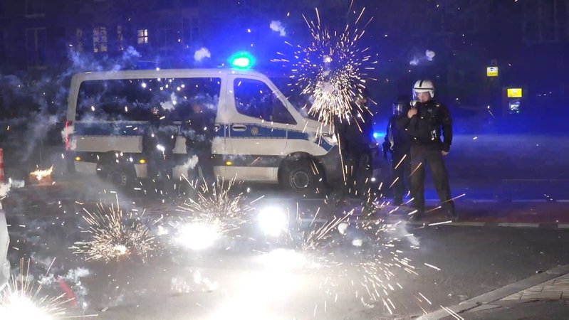 31.12.2022, Berlin: Polizeibeamte stehen hinter explodierendem Feuerwerk. Nach Angriffen auf Einsatzkräfte in der Silvesternacht hat die Diskussion um Konsequenzen begonnen.  
