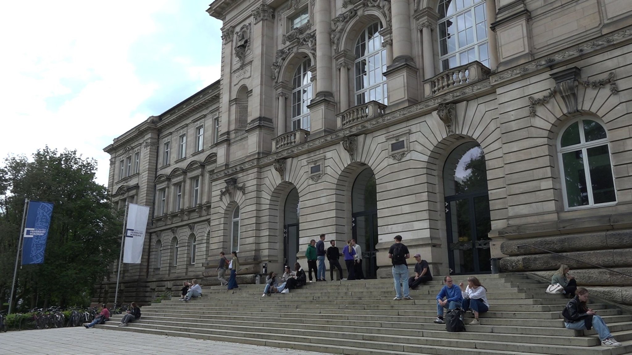 Studierende halten sich auf der Treppe eines Gebäudes der Universität Würzburg auf