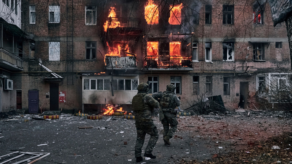 Ukrainische Soldaten laufen, um Menschen in einem Wohnhaus in Bachmut zu helfen, das nach einem Beschuss in Flammen steht.