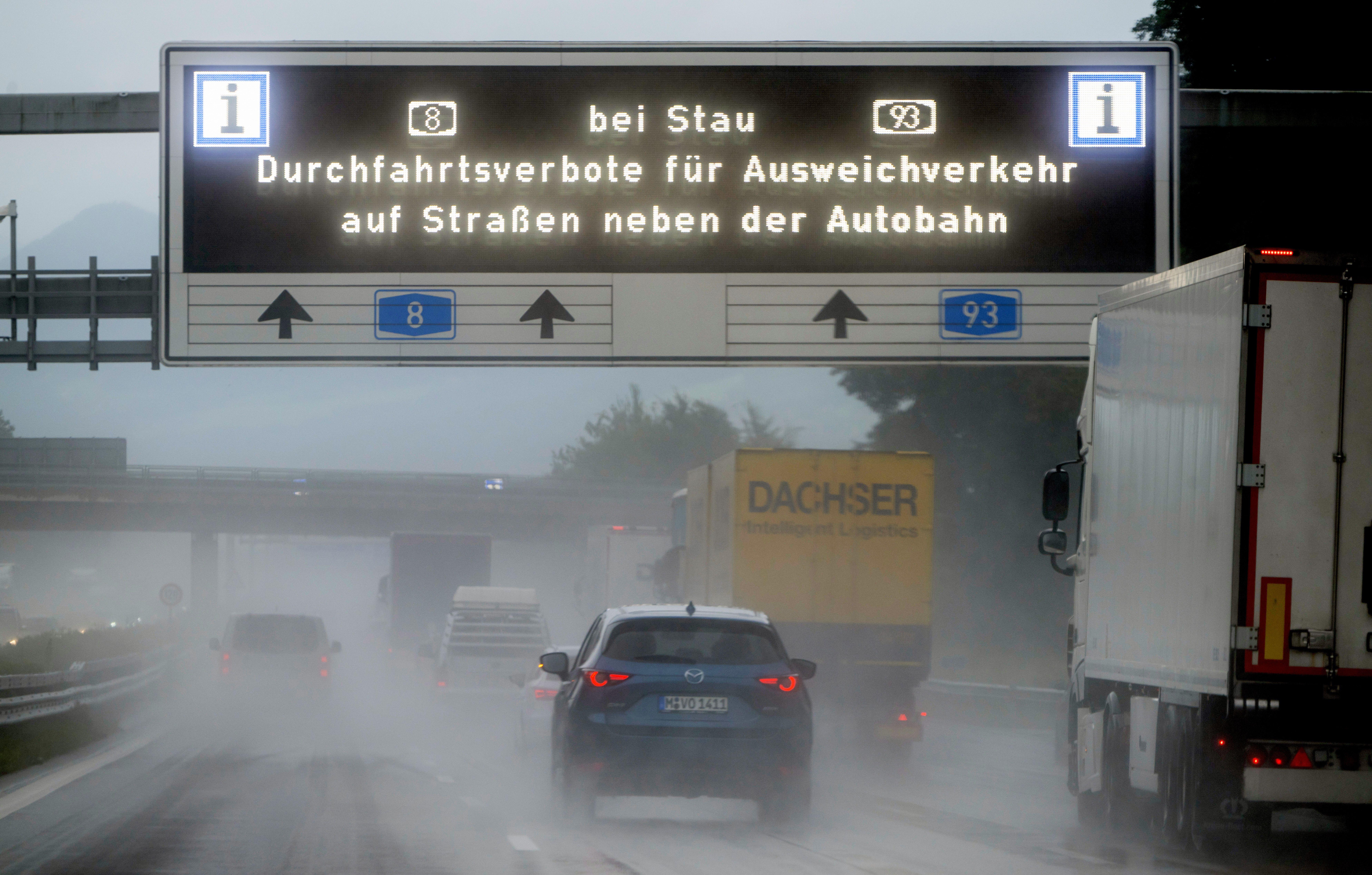 Ein digitale Anzeige mit der Aufschrift "Bei Stau Durchfahrtsverbote für Ausweichverkehr auf Straßen neben der Autobahn" hängt über der Autobahn A8.