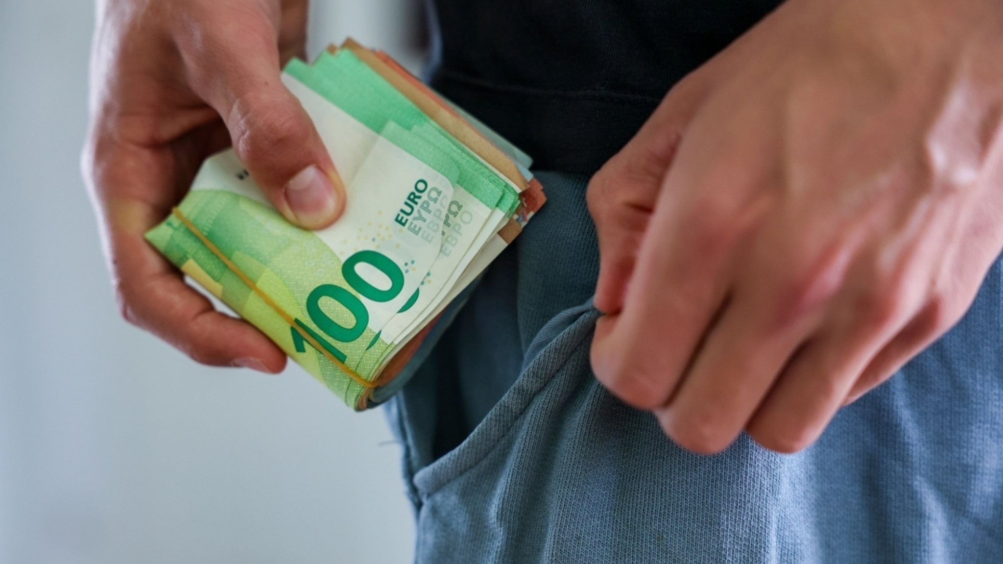 (Symbolbild) Eine Person steckt Bargeld in die Hosentasche | Bild: dpa-Bildfunk/Jan Woitas (Symbolbild) Eine Person steckt Bargeld in die Hosentasche