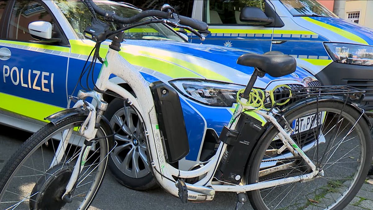 Ein weißes E-Bike steht vor einem Polizeiauto.