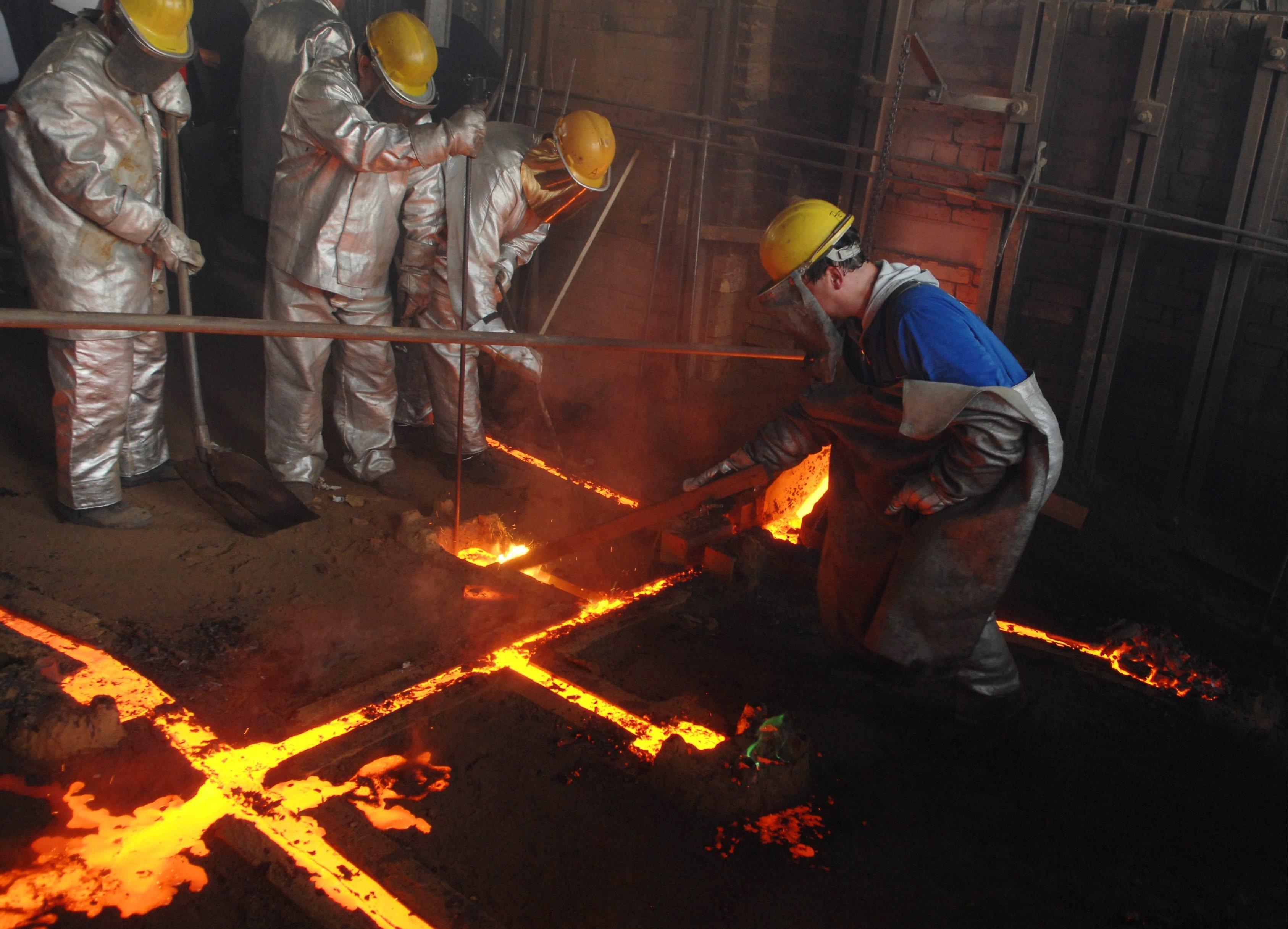 Mitarbeiter der Gießerei Perner gießen in Passau flüssiges Metall in eine Gussform