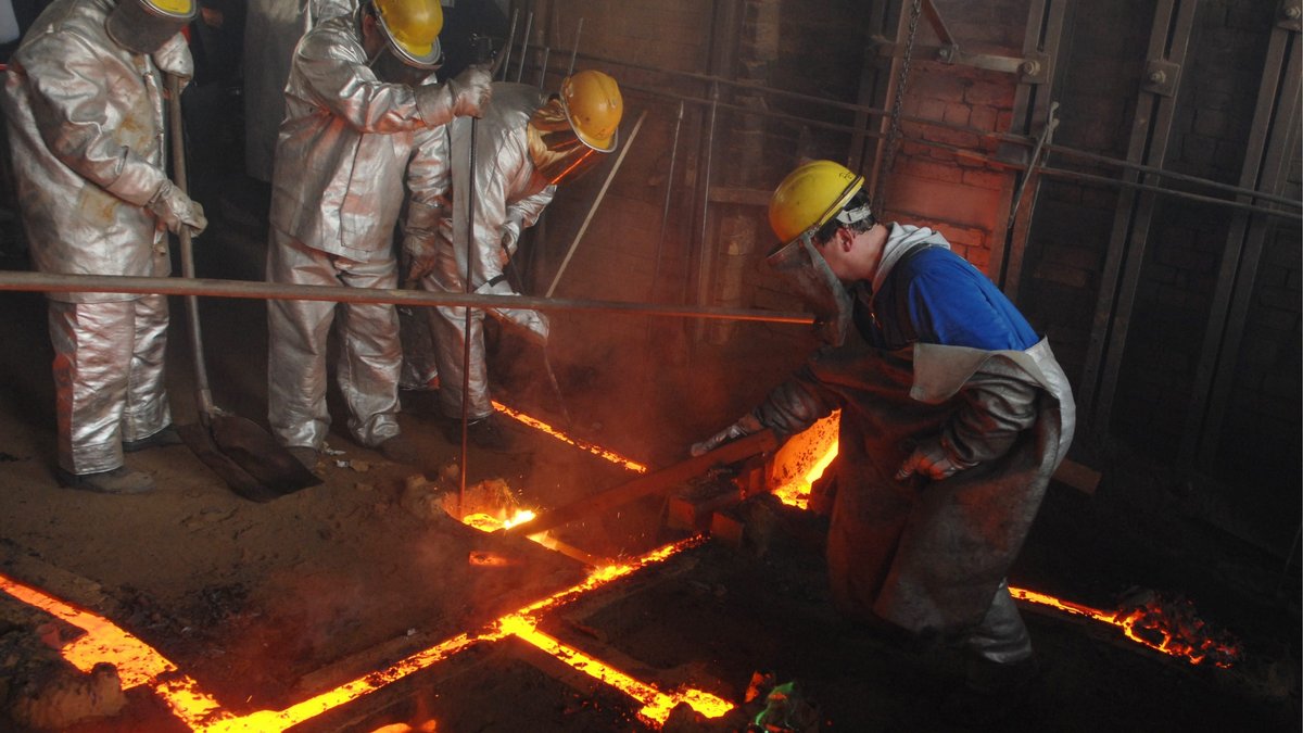 Mitarbeiter der Gießerei Perner gießen in Passau flüssiges Metall in eine Gussform
