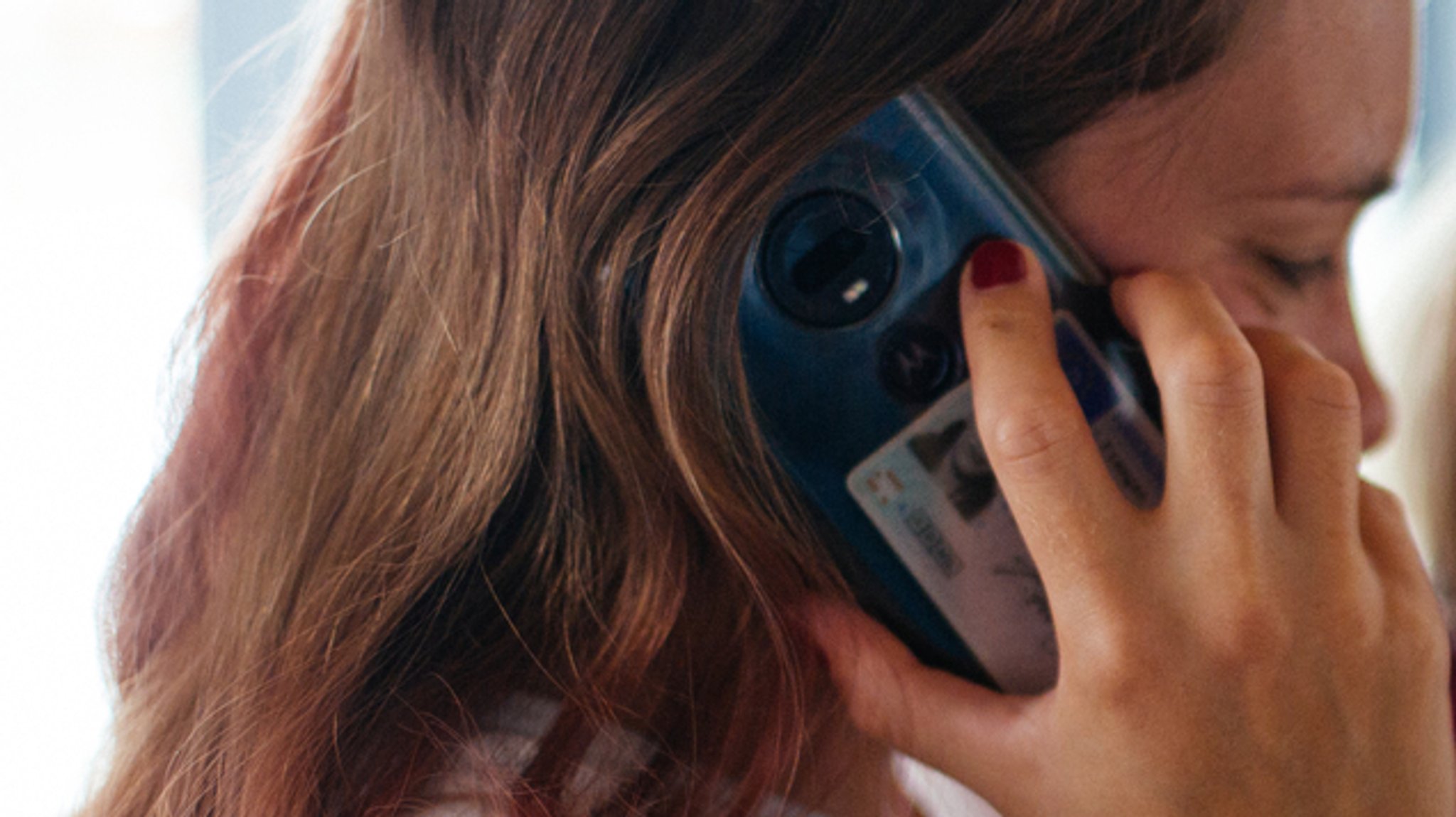 Eine Frau telefoniert mit ihrem Handy am Ohr.