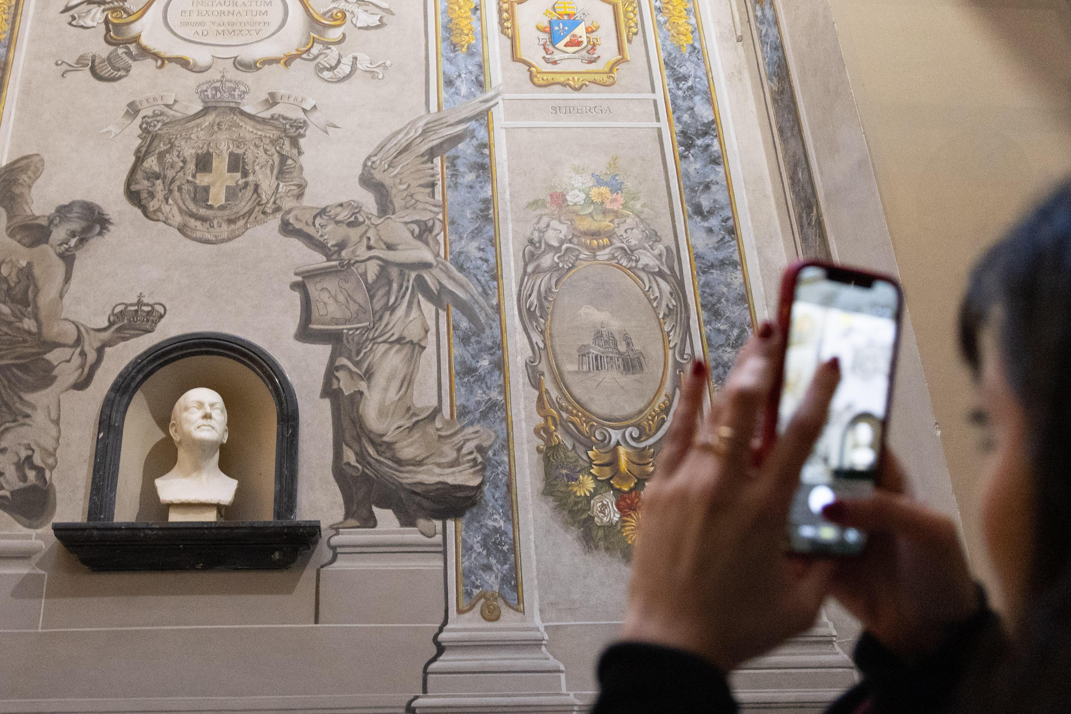 Ein Smartphone fotografiert das Fresko eines Engels. Er sieht aus wie Giorgia Meloni.