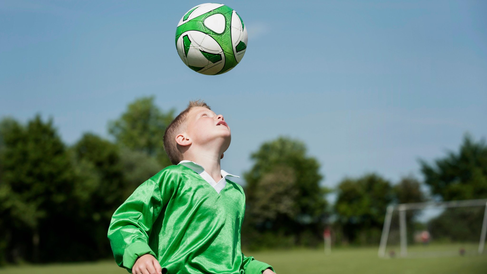 Kind trainiert Kopfbälle mit einem Fußball (Symbolbild)