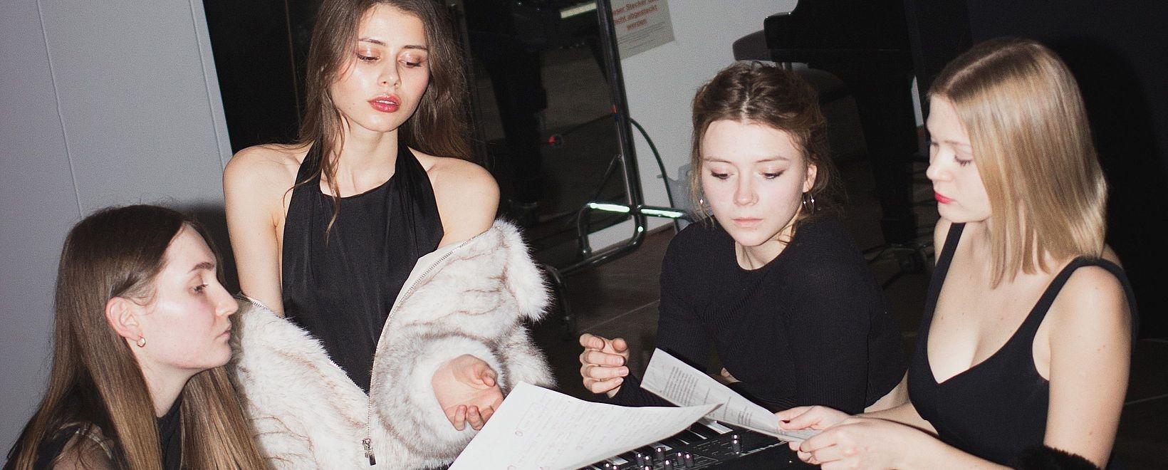 Drei Junge Frauen in schwarz mit Textblättern in der Hand