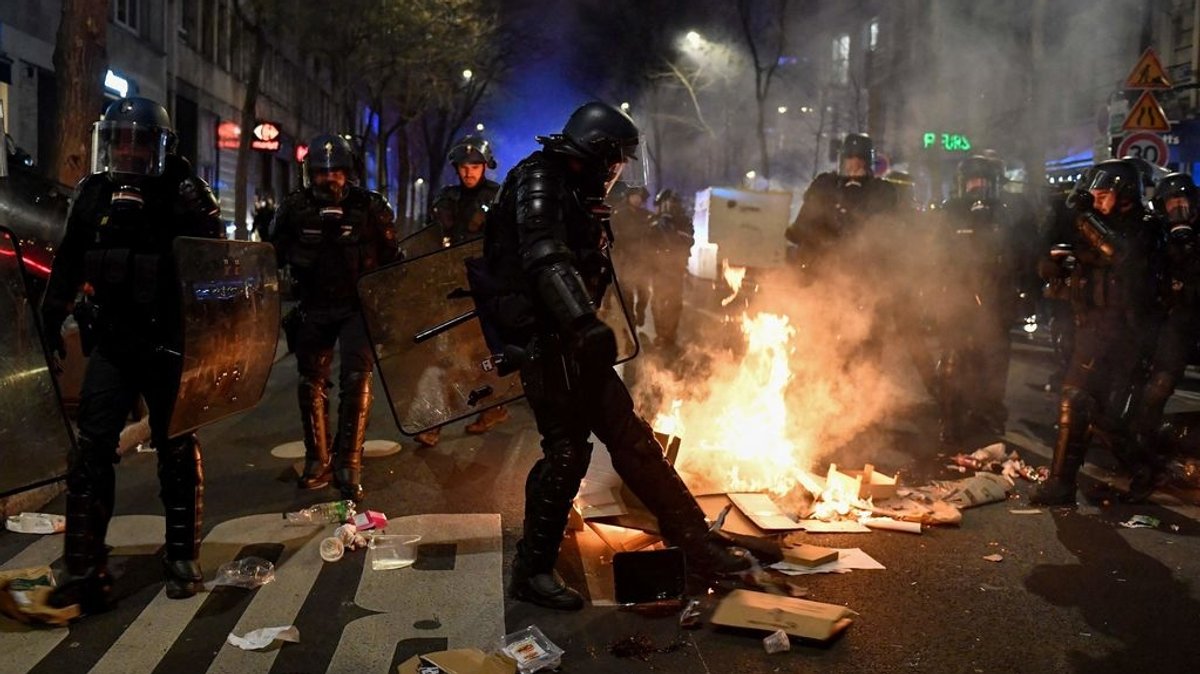Ein französischer Gendarm tritt während einer Demonstration gegen den Regierungsentscheid zur Rentenreform ein Feuer auf der Straße aus. 
